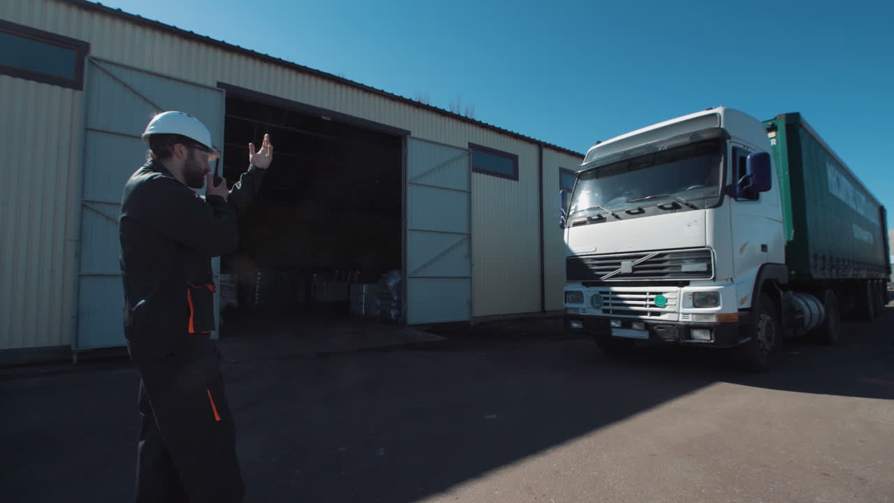 Worker directing a truck at a warehouse loading dock