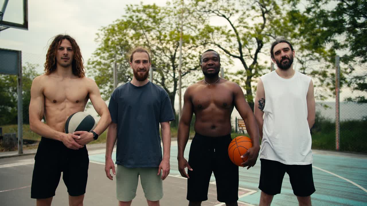 retrato de un equipo de baloncesto multirracial cuyos miembros están de pie, sonriendo y mirando a la cámara en el campo de baloncesto