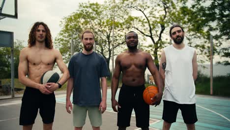 retrato de un equipo de baloncesto multirracial cuyos miembros están de pie, sonriendo y mirando a la cámara en el campo de baloncesto