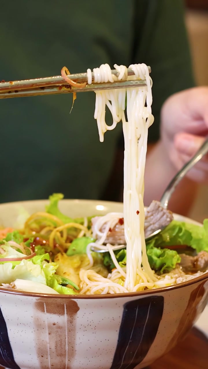 Persona che Prende Noodles da una Ciotola con le Bacchette