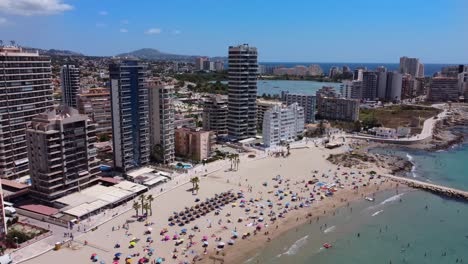 Turistas-En-La-Playa-De-Calpe-Con-El-Horizonte-De-Rascacielos-De-Fondo