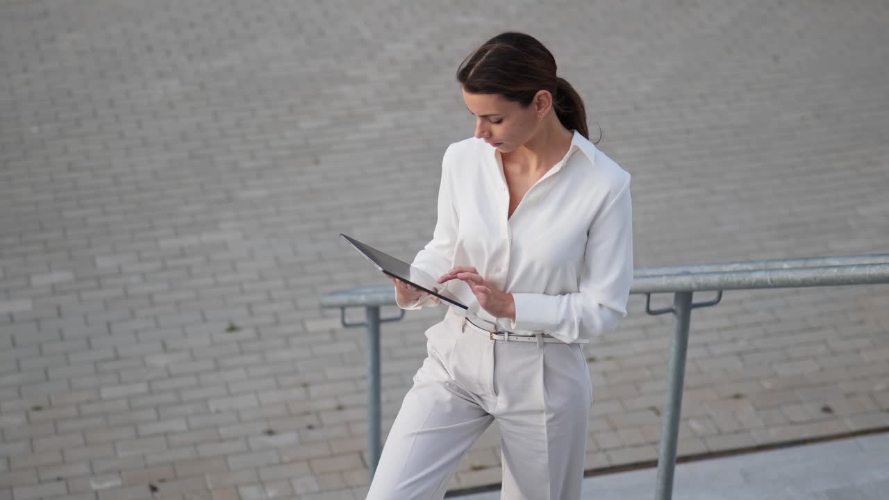 Push-in shot on a businesswoman staying on stairs and looking at her tablet