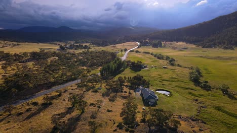 rural farm house and highway near kosciuszko national park with storm clouds and sun rays, crackenback, nsw, australia