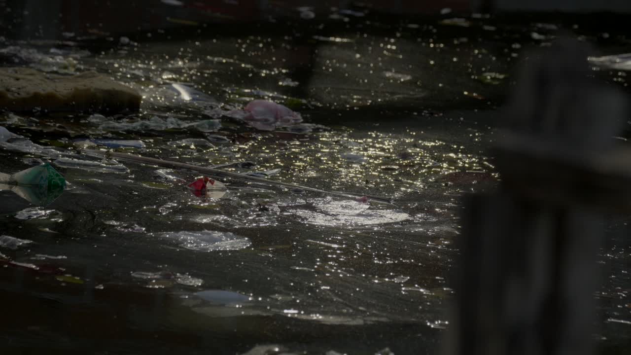 Garbage floats in a rotten stream and catches the reflection of the ...