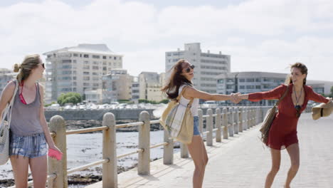 Three-young-women-tourists-dancing-on--on-beach-promenade-outdoors