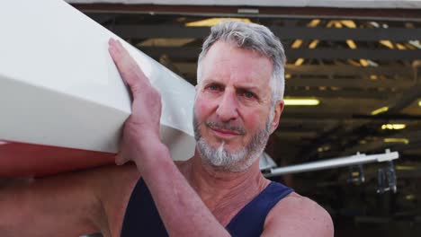 portrait of senior caucasian man carrying a rowing boat