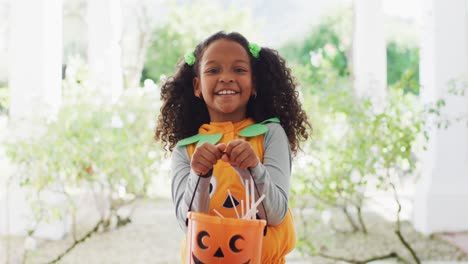 Video-portrait-of-happy-african-american-girl-trick-or-treating-for-halloween