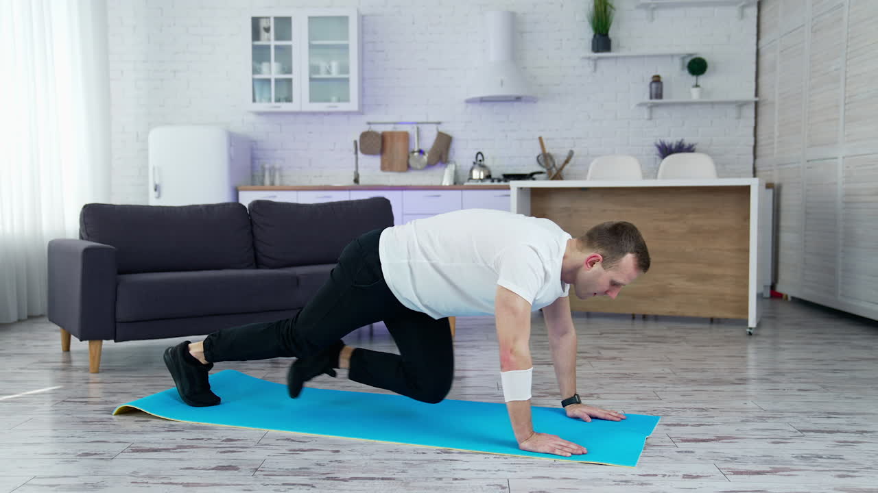 Sportsman exercising in the kitchen. Young man doing fitness exercises on a mat at home during lockdown. Wellness and healthy lifestyle.