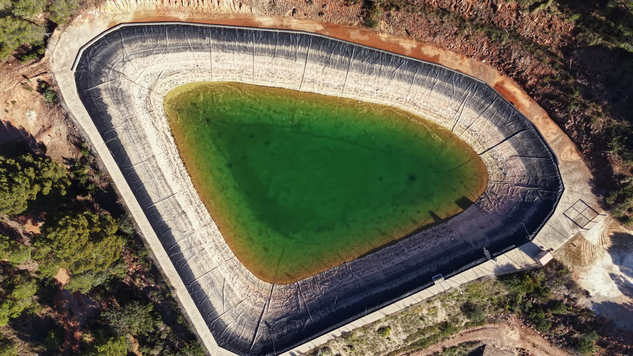 Acqua verde riempie un grande stagno artificiale in un cantiere edile di giorno
