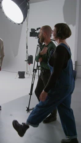 Vertical-Video-Of-Film-Crew-And-Female-Director-Congratulating-Actors-After-Performance-Shooting-Movie-In-Studio-Shot-In-Real-Time