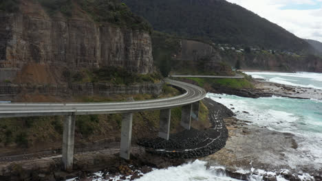 drone flying around the curving sea cliff bridge