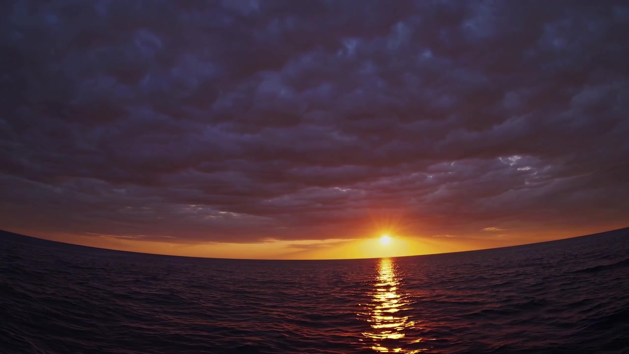 Dramatischer Sonnenuntergang über dem Ozean mit dunklen Wolken