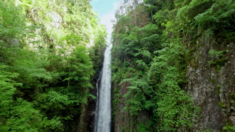 Majestic-waterfall-cascading-down-rocky-cliffs-surrounded-by-lush-green-forest