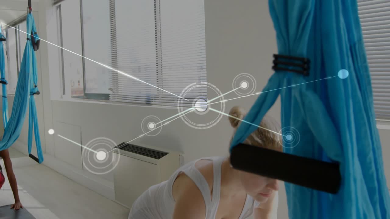 Woman adjusting turquoise hammock in yoga studio initiating network overlay for motion tracking