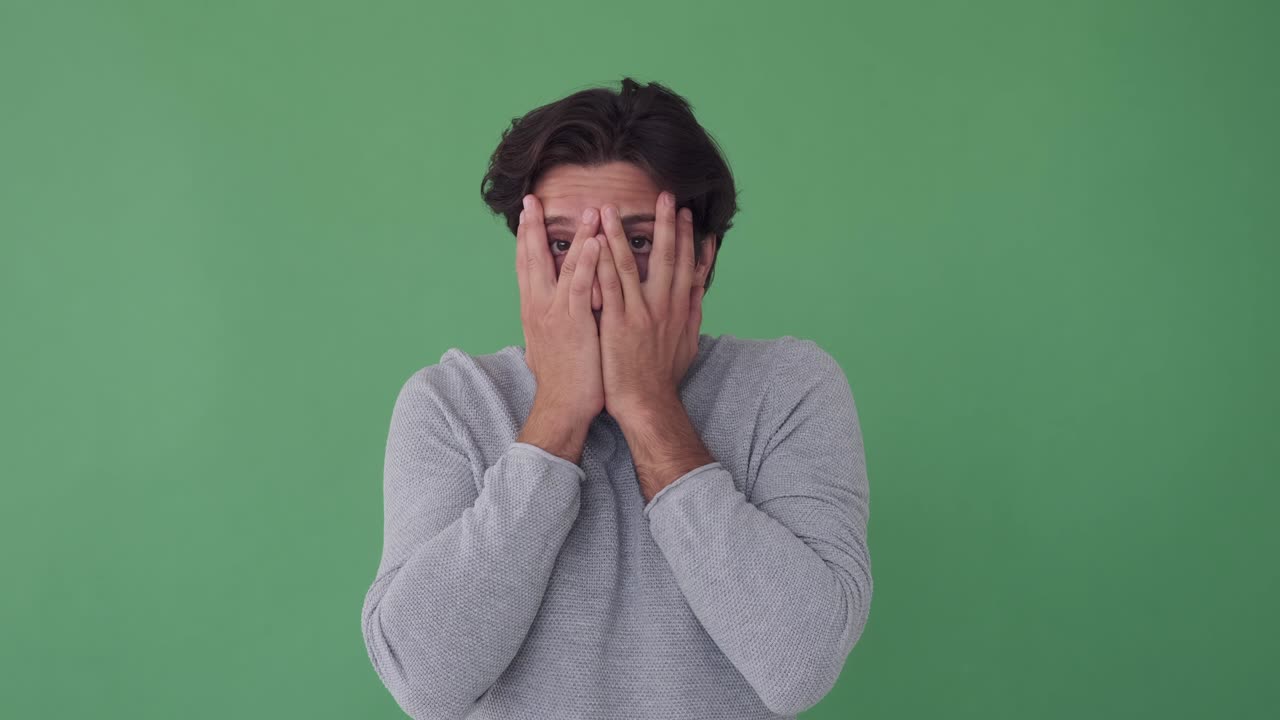 hombre cubriendo su cara y mira hacia fuera de las manos