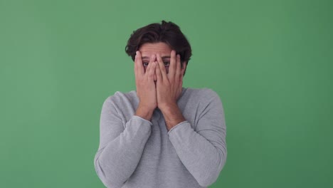 hombre cubriendo su cara y mira hacia fuera de las manos