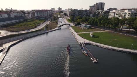 Cinematic-aerial-shot-of-a-moliceiro-boat-travelling-toward-the-narrow-water-canal-in-Aveiro