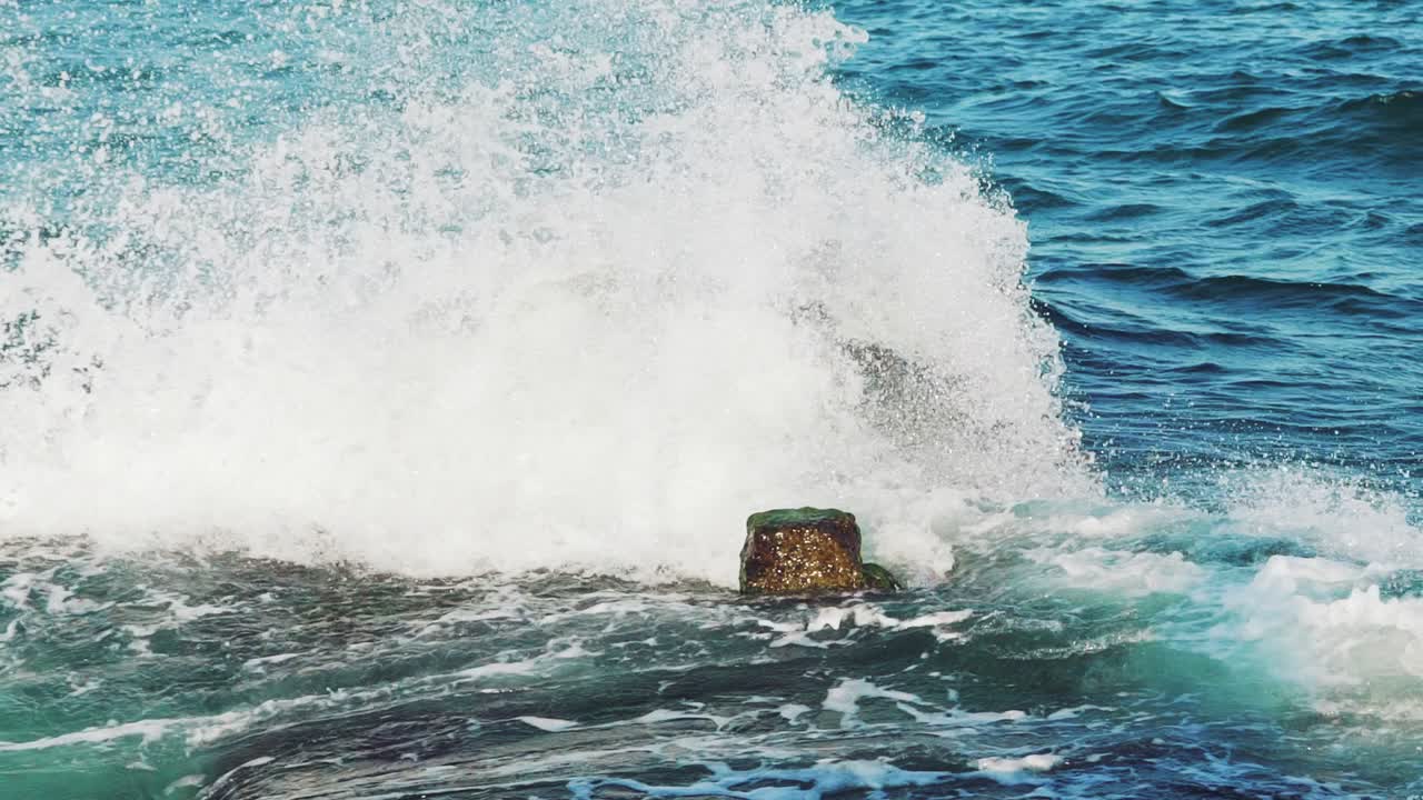 Sea. Splashes of the wave scatter from the impact of the breakwater. Slow motion.