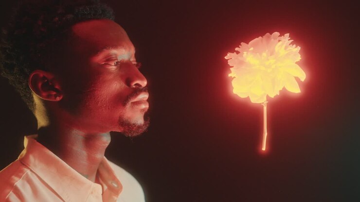 Retrato de Jovem Homem Negro ao Lado de Flor Brilhante Levitando no Ar
