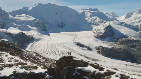 outdoor lovers standing on rocky viewpoint overlooking large pers glacier