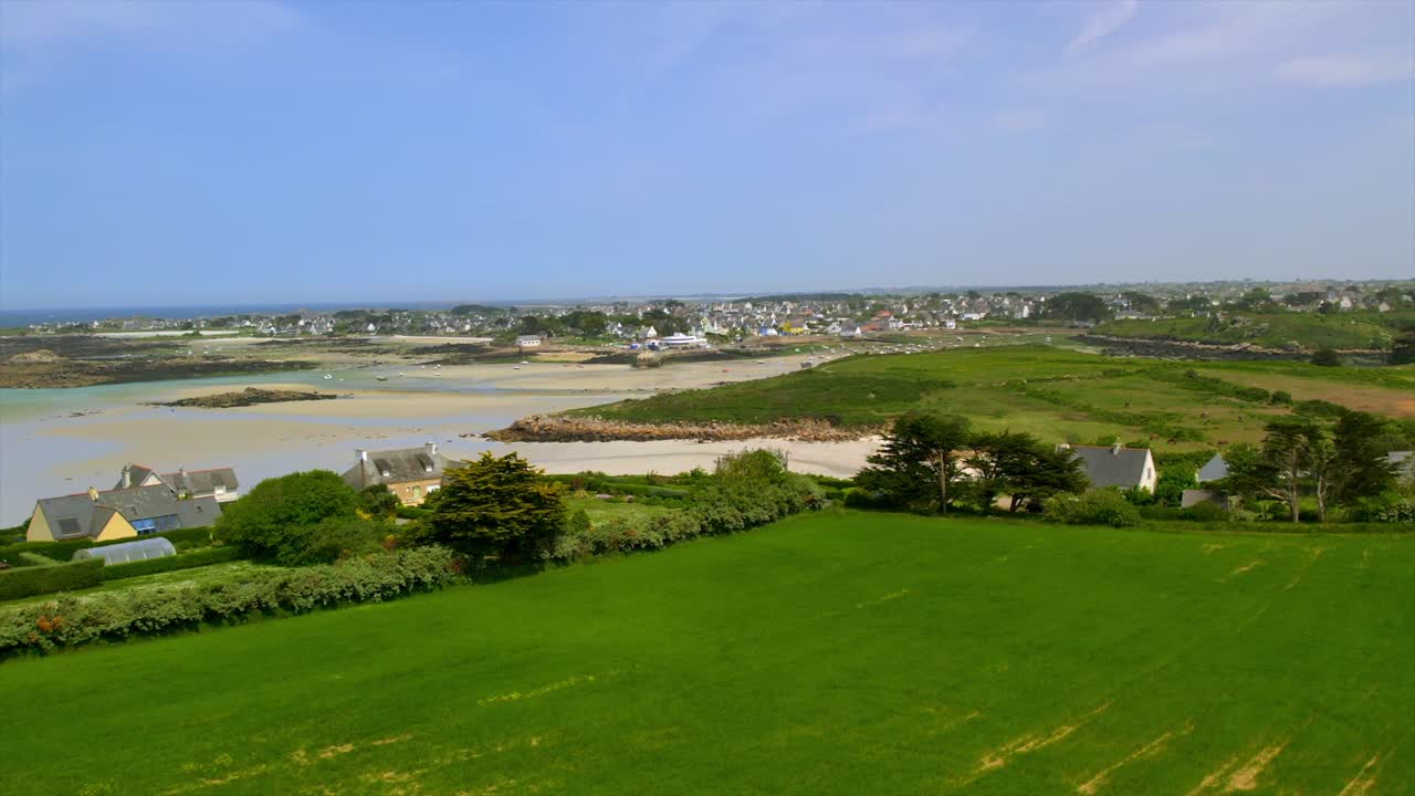 Slow-motion drone footage showing green fields leading to a coastal village and scenic shoreline in Brittany, France. Perfect for highlighting rural coastal charm and European countryside.