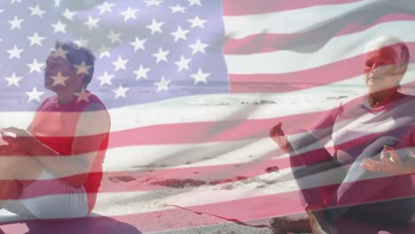 animación de la bandera de los estados unidos de américa sobre una pareja biracial mayor practicando yoga en la playa