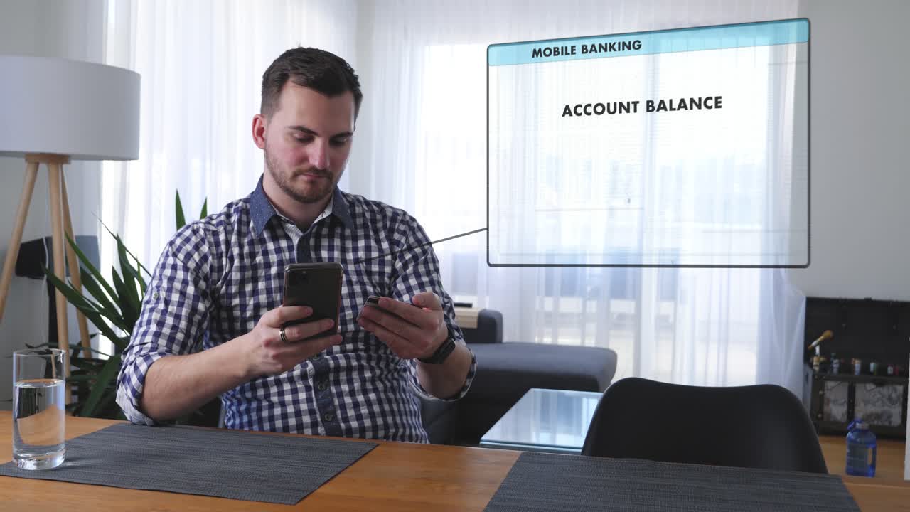 Young man at the living room table checks his account balance with an online banking app on his smartphone