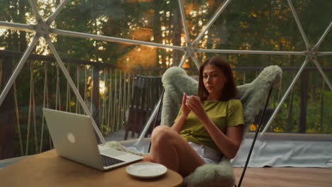 balanced woman sits comfortably holding cup of coffee in hands. young woman alone looks with thoughtful deep look without changing emotions