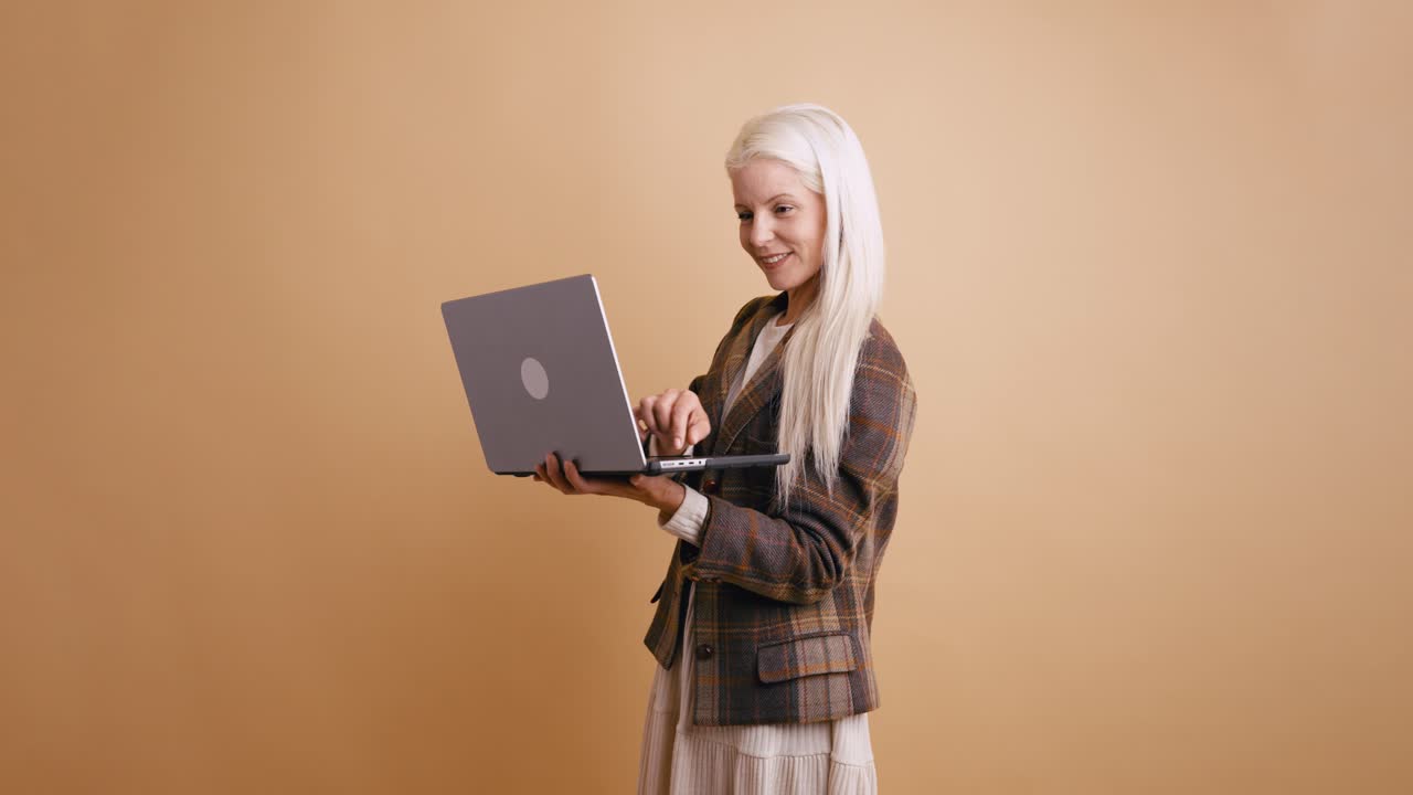 Lächelnde blonde Frau tippt am Laptop im Studio