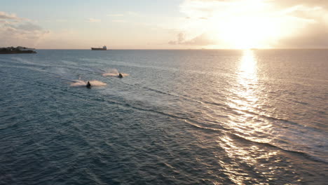 Aerial-fly-over-three-jet-skis-full-speed-ride-on-caribbean-coast-together-have-fun-with-sunset-over-horizon