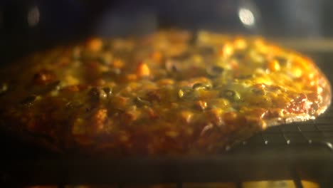Pizza bubbling in oven - Homemade pizza cooking baking in hot oven with cheese bubbling. Cooking Italian pizza in electric convection oven. Closeup of pizza topped with  olives mozzarella and cheddar