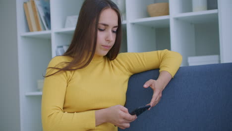 Mujer-Usando-Teléfono-Inteligente.-Chica-Guapa-Usando-La-Pantalla-Táctil-Del-Teléfono-Inteligente-Moderno-Y-Sonriendo-En-Casa