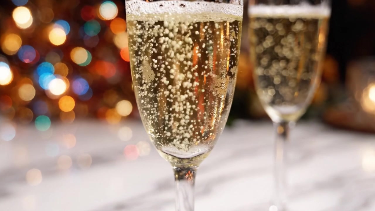 Brindisi di celebrazione: Bicchieri di champagne frizzante con bollicine che evidenziano un'atmosfera festosa e uno sfondo bokeh colorato, perfetto per Capodanno o occasioni speciali.
