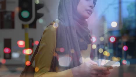 animation of asian woman in hijab using smartphone over cityscape