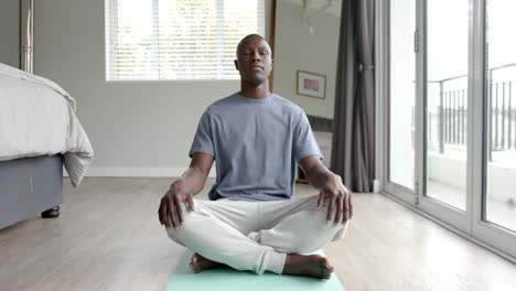 African-american-man-doing-yoga-and-meditating-at-home,-slow-motion