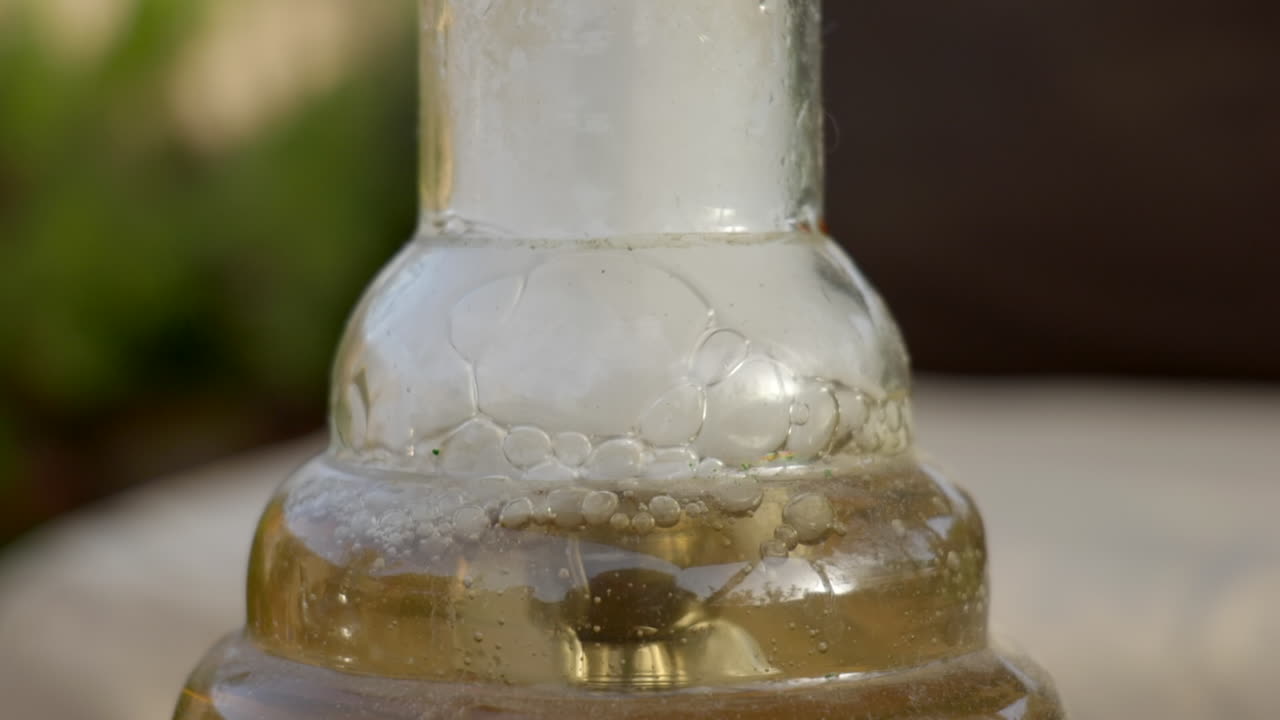 시샤에서 거품이 이는 물과 연기의 짐벌 샷을 닫습니다.