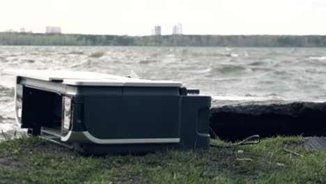 impresora siendo destruida por un martillo cerca de una orilla del río