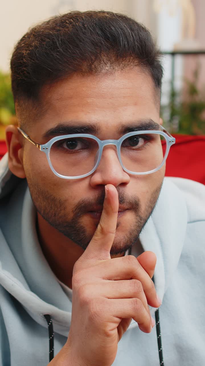Indian man presses finger to lips makes silence hush sign do not tells gossip secret quiet