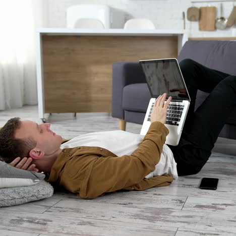 man with laptop on floor. young man using laptop at home, lying on the floor