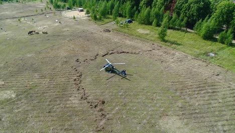 helicopter landing in a field with people and forest background