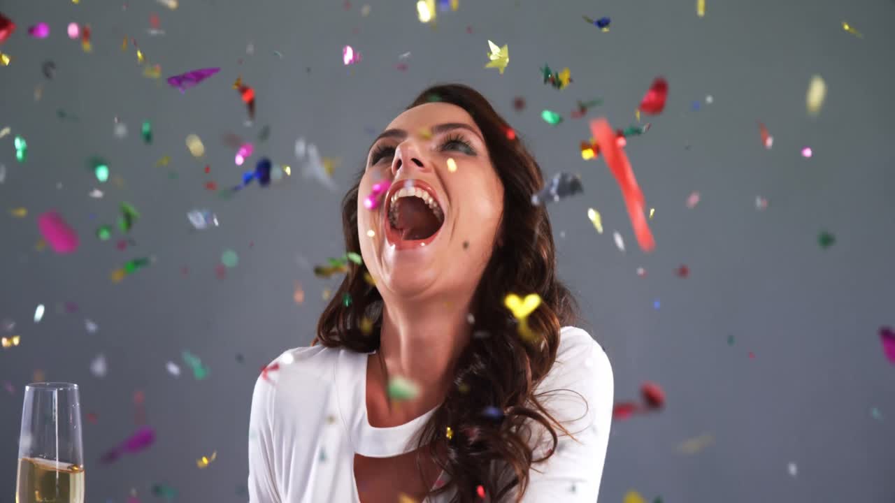 donna eccitata con bicchiere di champagne che guarda il confetti 4k