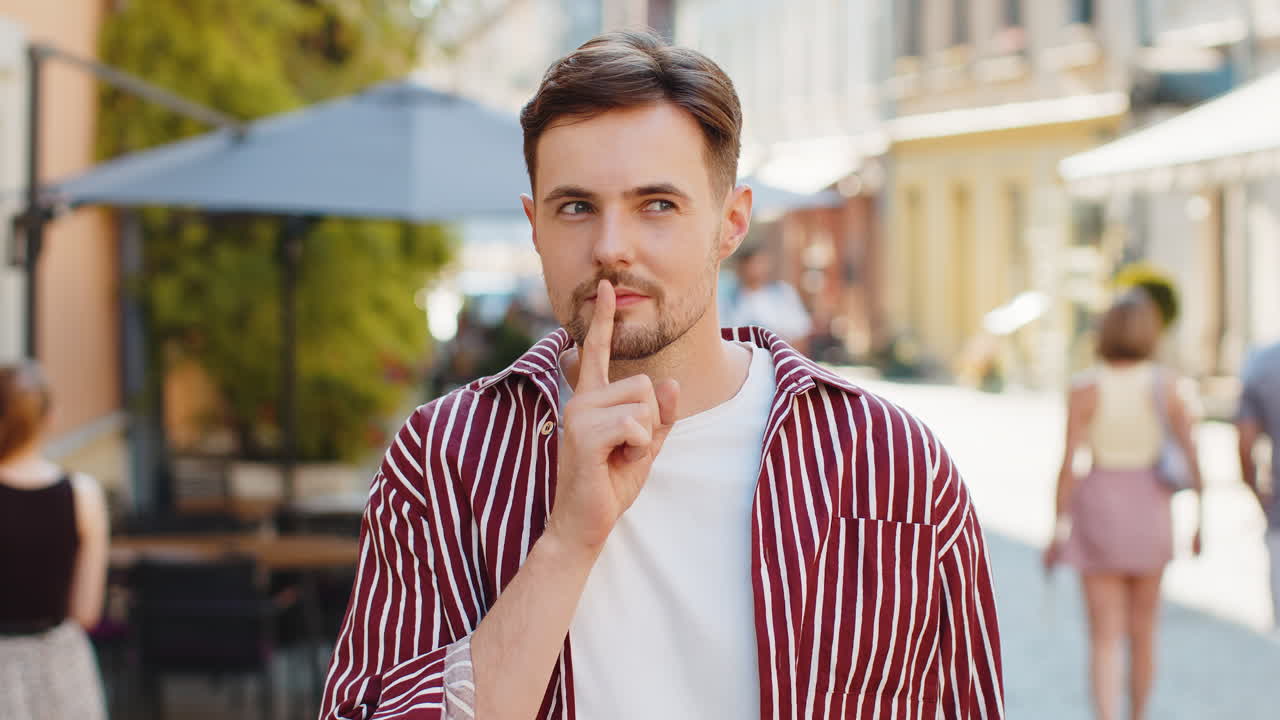 Adult man presses finger to lips makes silence hush sign do not tells gossip secret quiet in city
