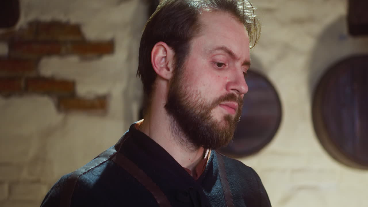 el hombre preocupado está de acuerdo con su amigo en la taberna medieval. el valiente hombre barbudo se une a una peligrosa búsqueda asintiendo con la cabeza en la posada.