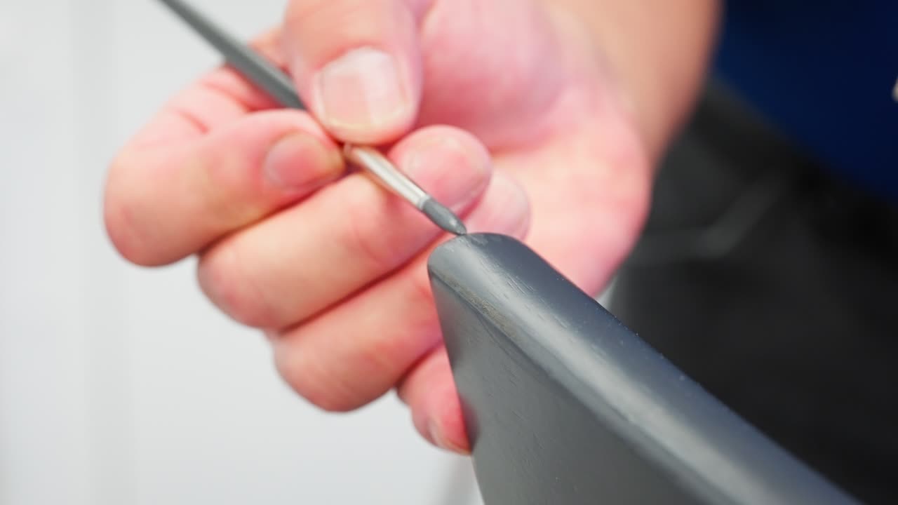 Slow Motion Meticulous painting of grey chair corner with small brush and mix palette