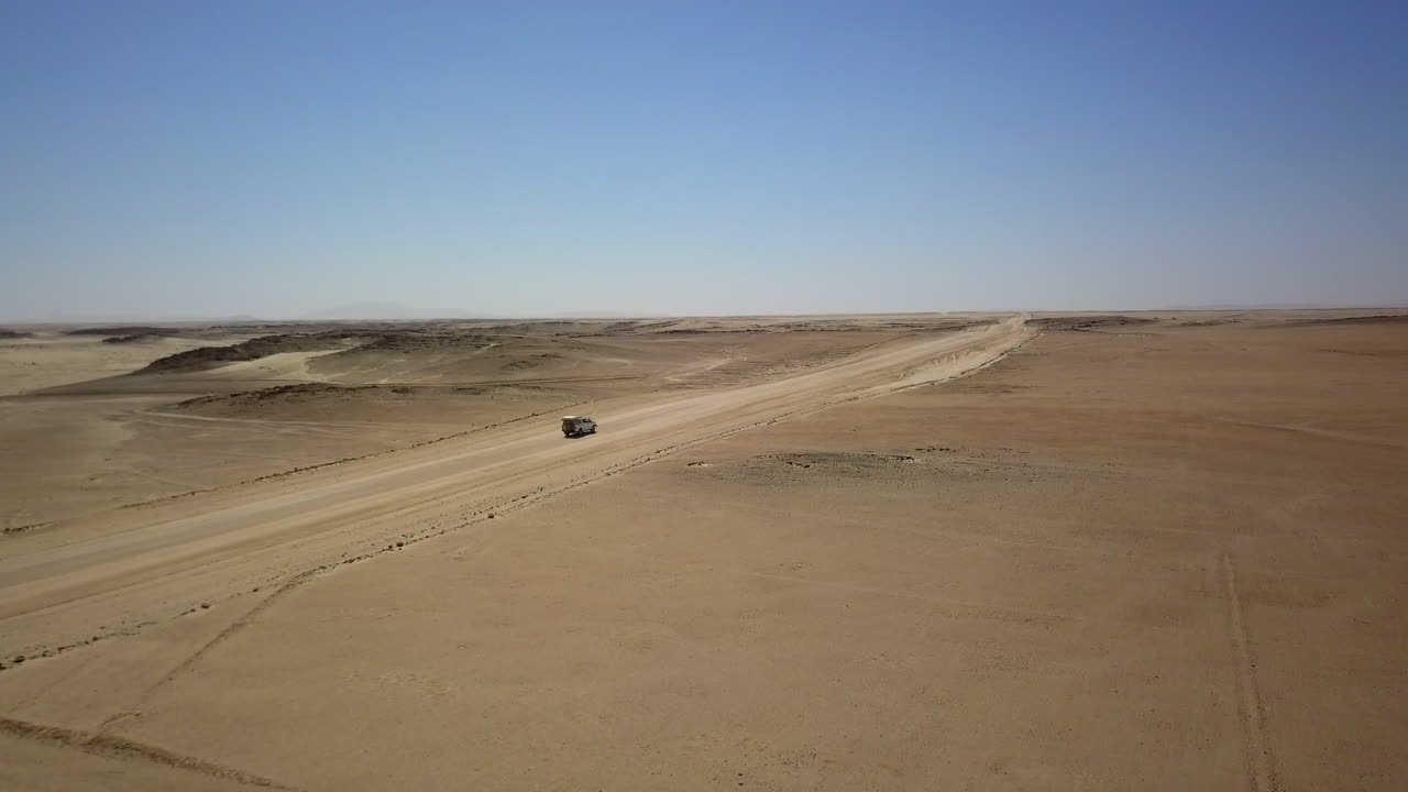 breathtaking drone view of a Jeep navigating Namibia's vast landscapes, showcasing stunning deserts, rugged terrain, and endless horizons in an epic adventure through nature's beauty.