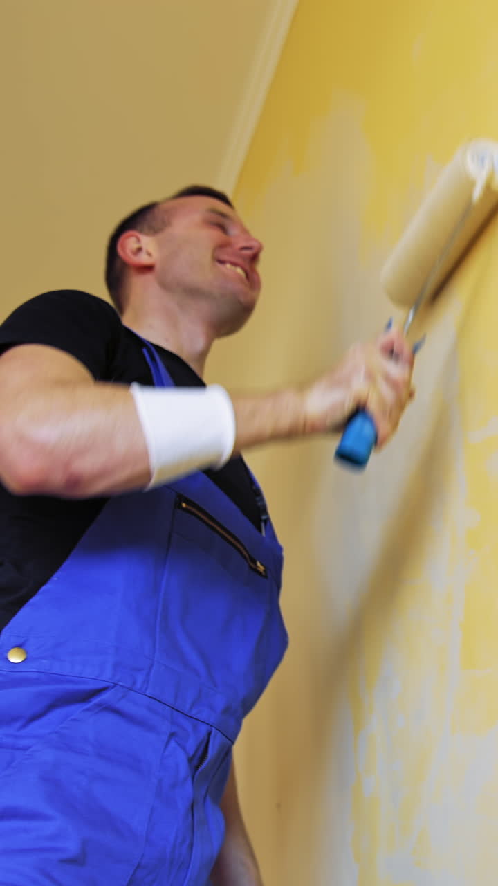 Man singing in paint brush. Cheerful man with rollers for painting the walls singing