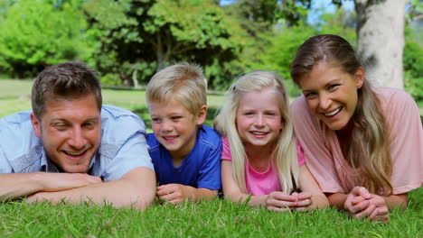 family lying together before looking up and laughing as they talk to each other