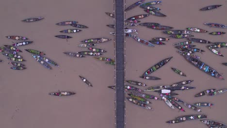 traditional wooden boats with food floating on brown river in indonesia under bridge