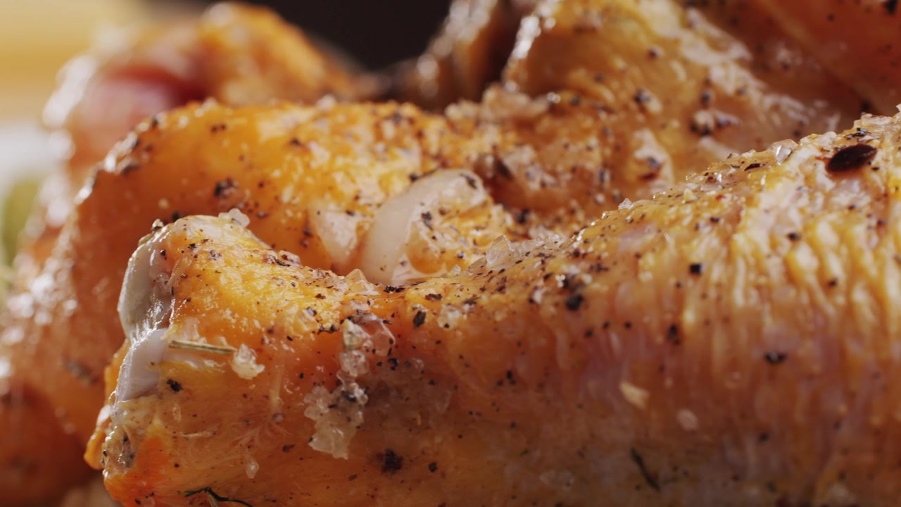 Primo piano di pezzi di pollo crudo conditi con sale e pepe