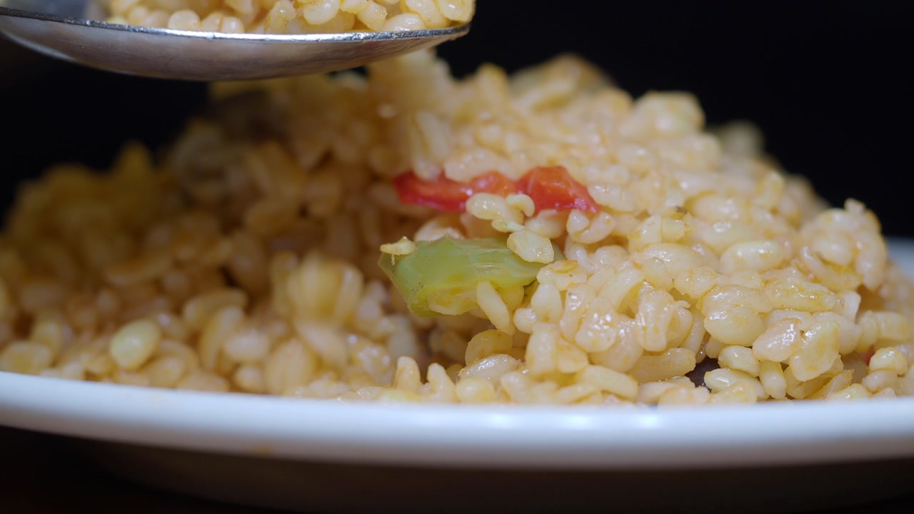 Close-up of a Spoon Scooping Delicious Rice Pilaf with Vegetables